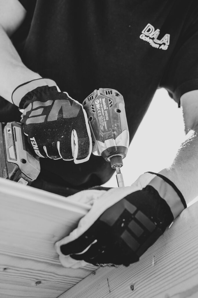A carpenter with work gloves roofs a building.